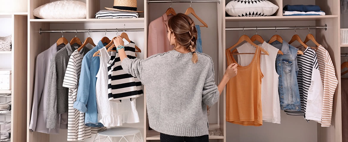 a woman hanging up her clothes in a closet