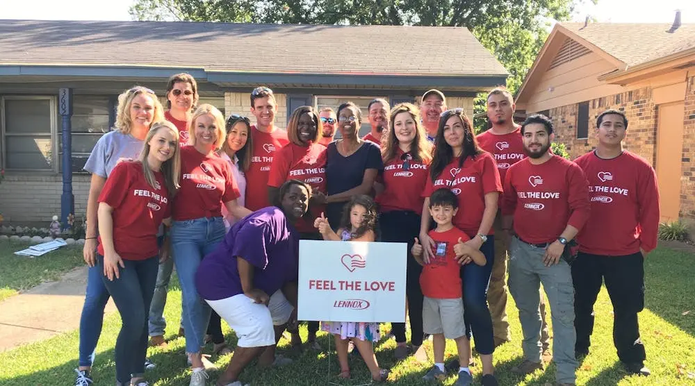 Lennox Feel the Love volunteers standing together while presenting a free air conditioner to a homeowner in need