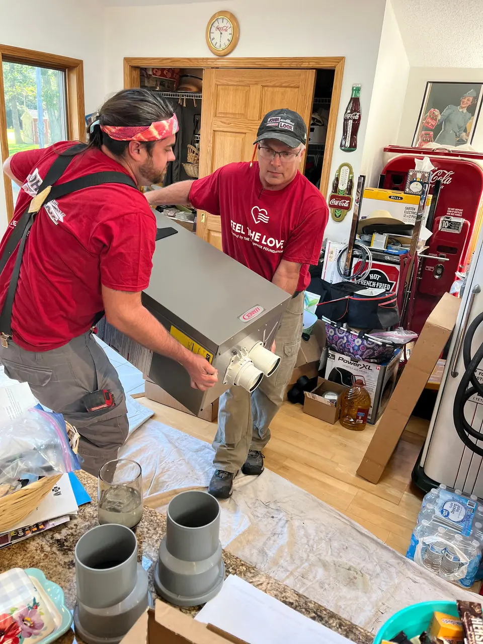 Person in a red Lennox shirt standing outside near an HVAC service van labeled “JOHN.”